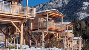 A wooden chalet with multiple balconies and a mountain backdrop. - Chalets & Glamping Nassfeld by ALPS RESORTS (Kotschach-Mauthen)