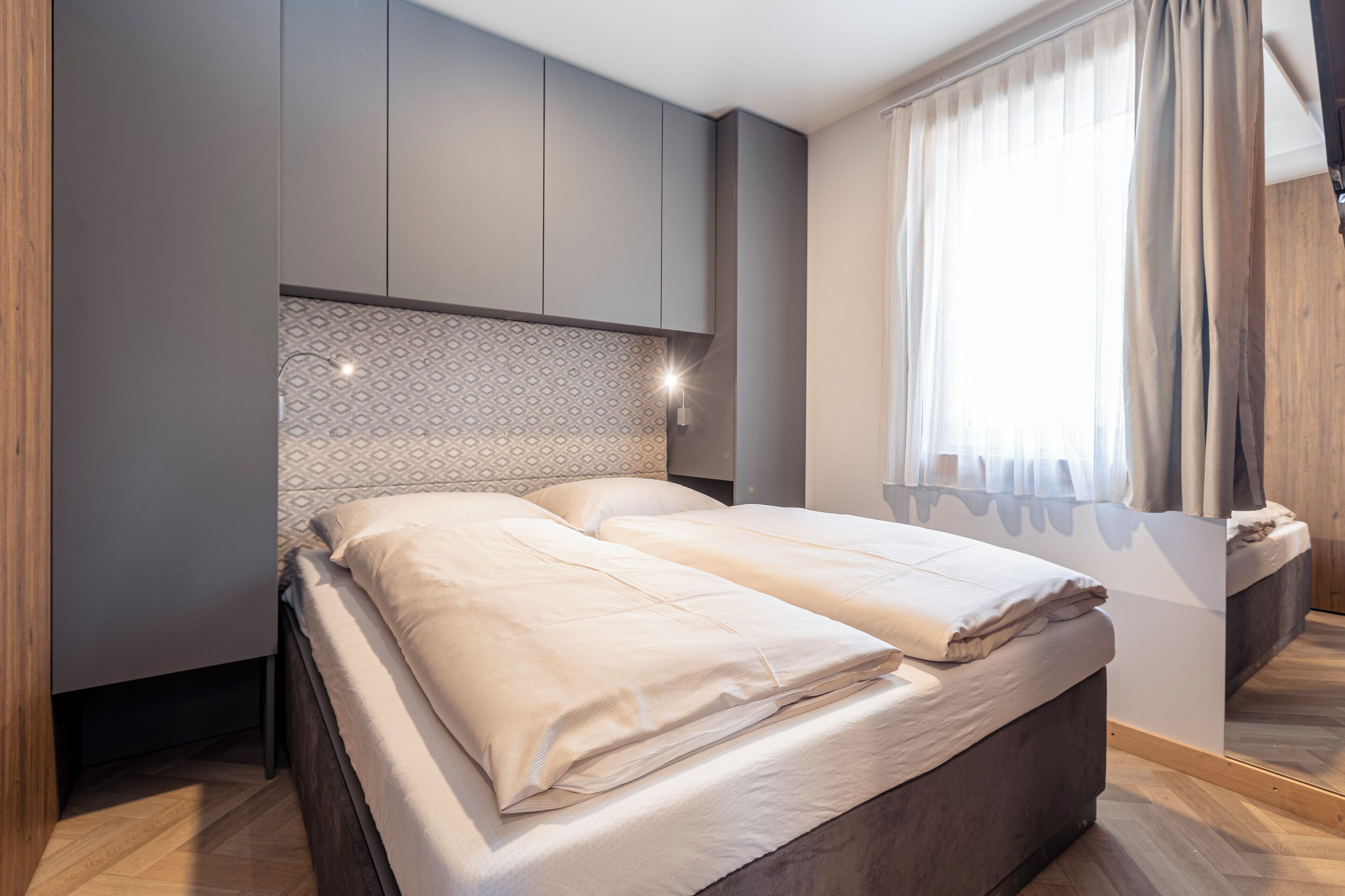 A modern bedroom with a bed, built-in wardrobe, and a window with curtains.