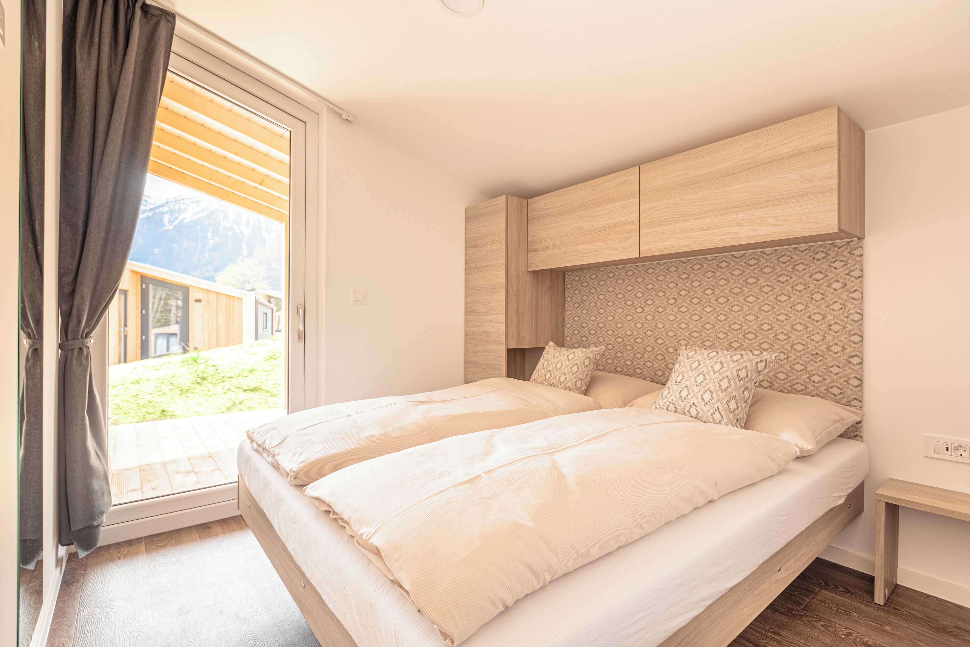 A bedroom with two beds, a wooden headboard, and a view of a mountain.