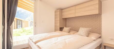 A bedroom with two beds, a wooden headboard, and a view of a mountain.