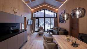Un interior moderno con cocina, zona de estar y ventanas amplias que ofrecen vistas a la montaña.