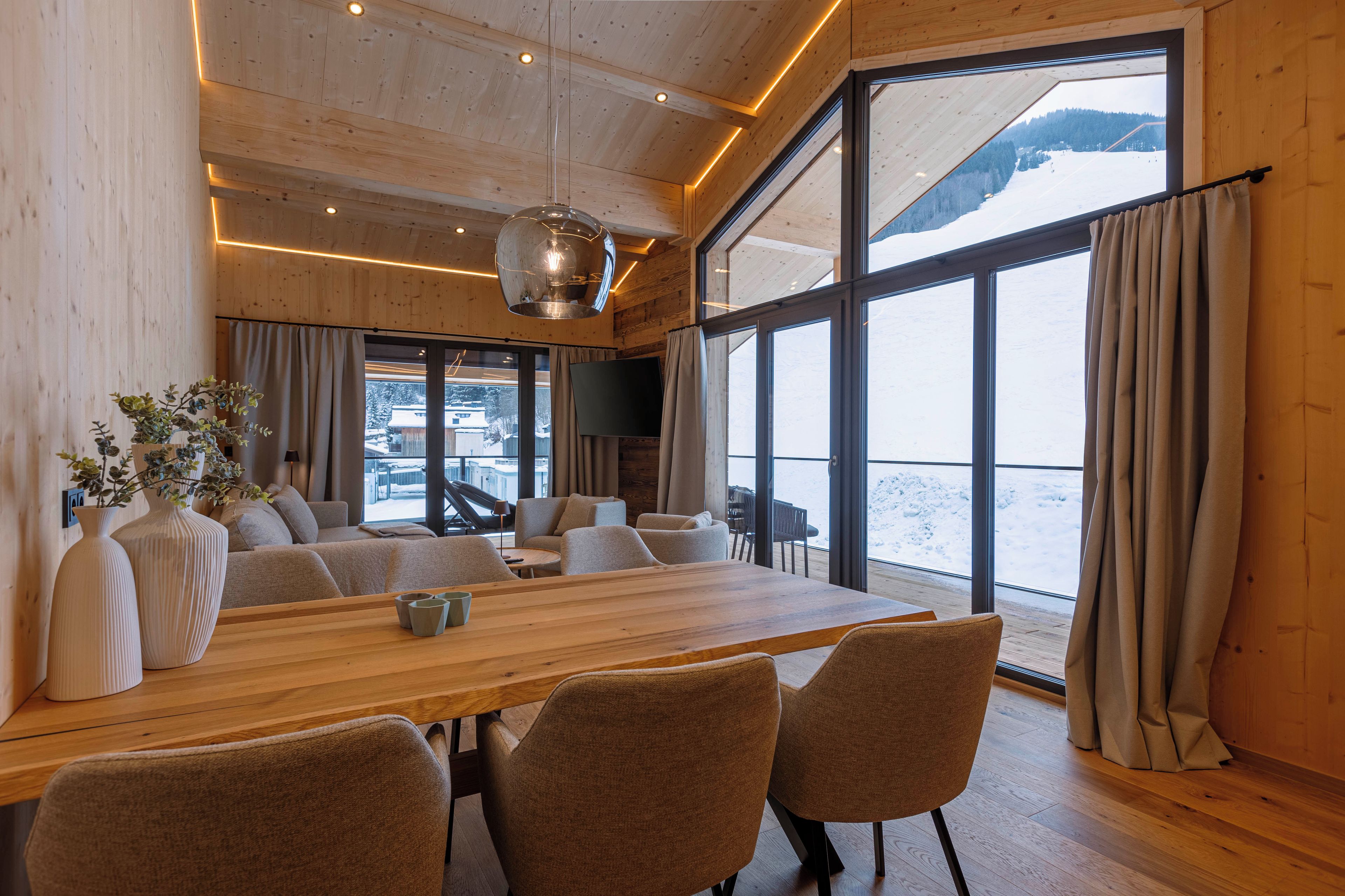 A spacious room with a large wooden table, several chairs, and a television.