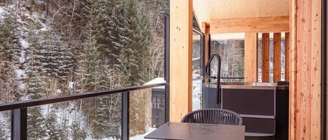 A wooden cabin with a balcony, a table, and a chair.