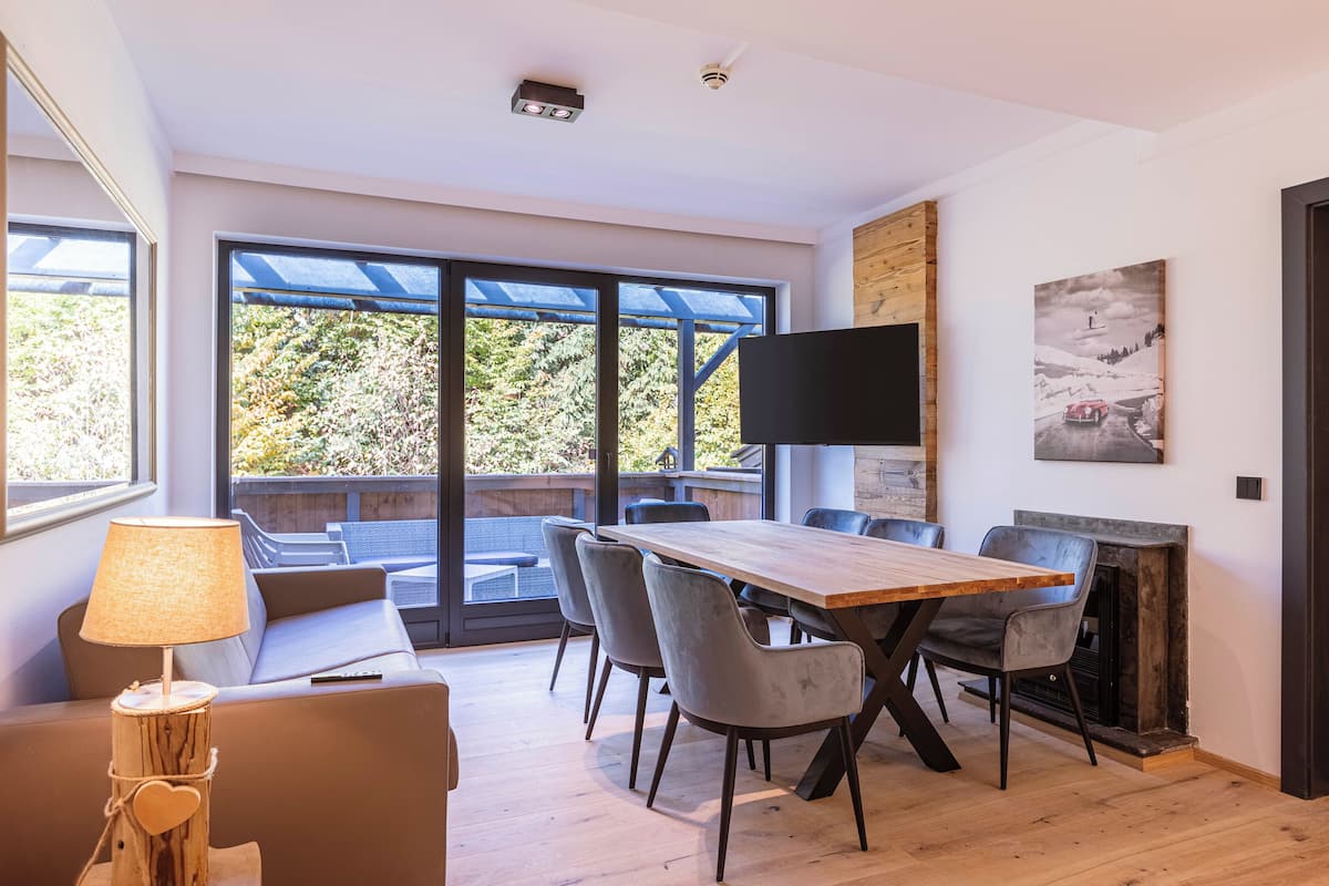 Ein moderner Essbereich mit einem Holztisch, grauen Stühlen, einer Couch und einem Kamin.