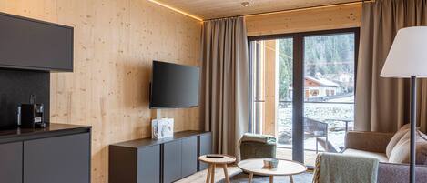 Ein modernes Wohnzimmer mit Flachbildfernseher, einer Couch, einem Couchtisch und einem Essbereich mit Tisch und Stühlen.