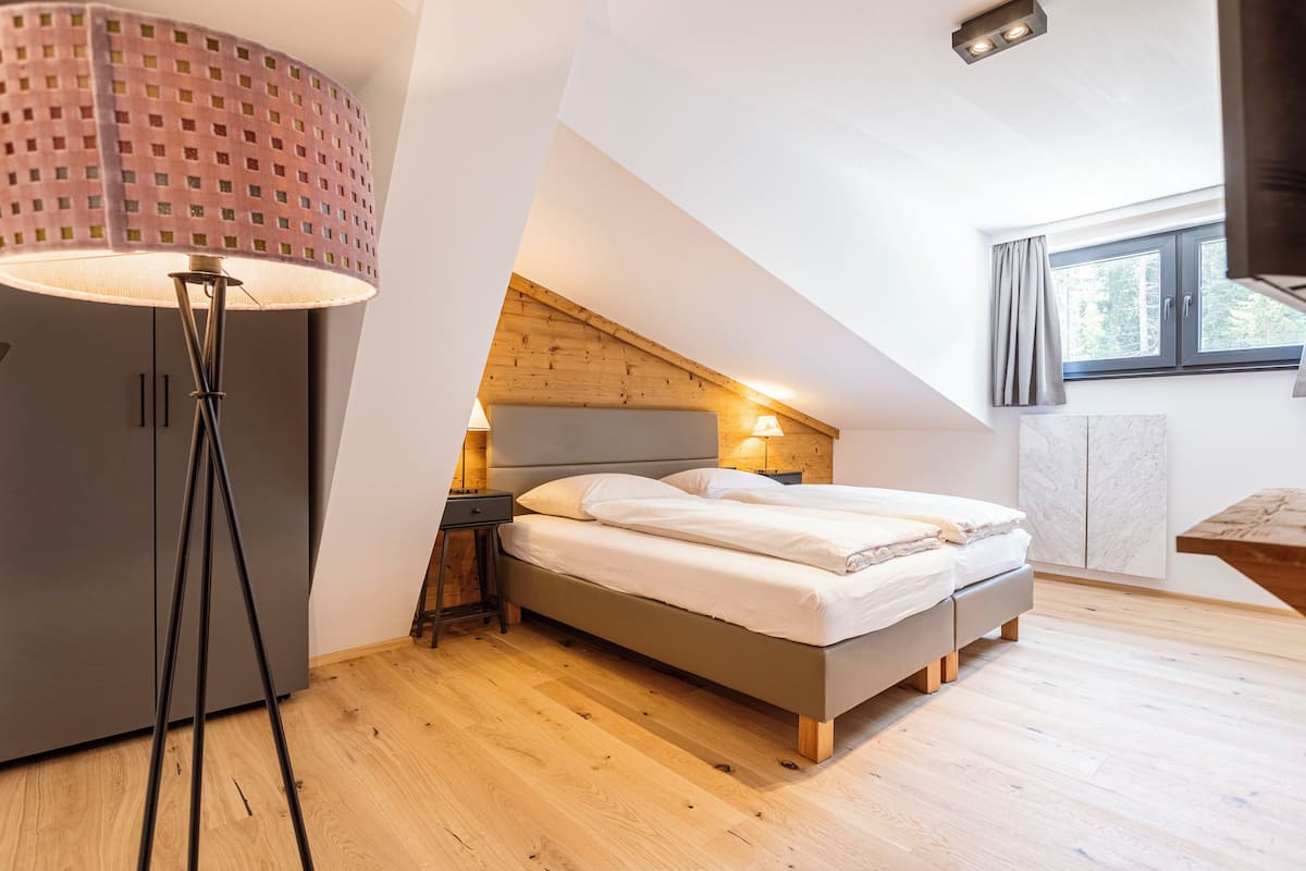 Ein Schlafzimmer mit einem Bett, Nachttischlampen, einer Stehlampe, einem Kleiderschrank und einem Fenster mit Vorhängen.