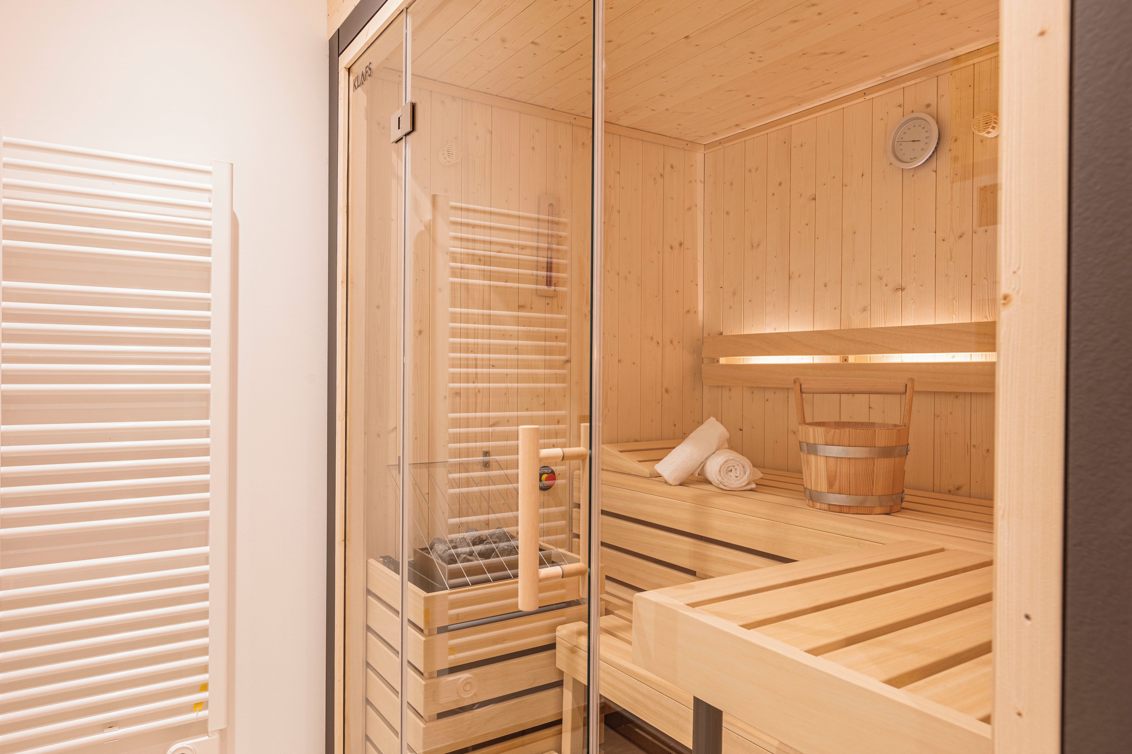 Ein Saunaraum mit Holzbänken und einer Glastür.