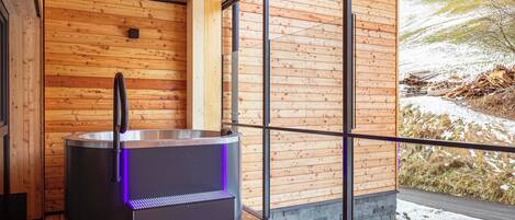 A sauna with a wooden interior and a view of a snowy landscape through large windows.