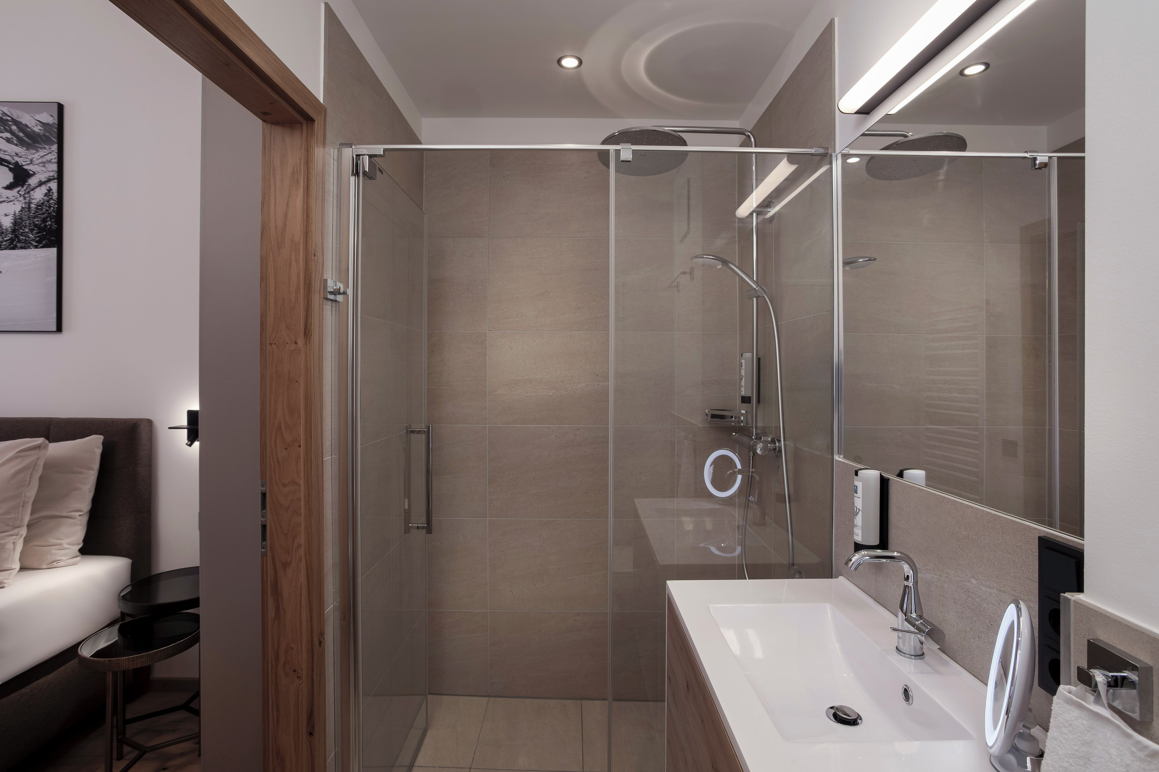 Une salle de bain moderne avec une douche à parois de verre, un lavabo blanc et un grand miroir.