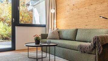 Una sala moderna con un sofá verde, una mesita redonda y una planta en maceta.