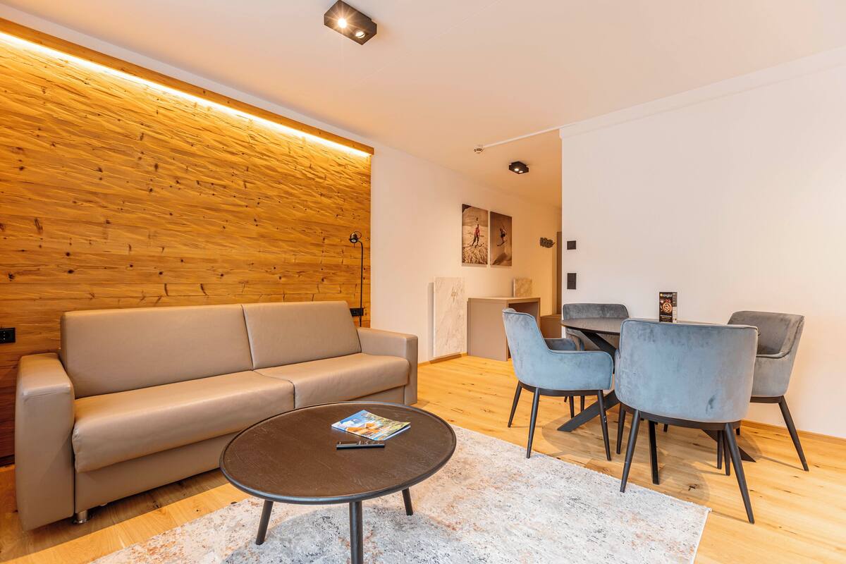 Ein modernes Wohnzimmer mit einer Couch, einem Couchtisch und einem Essbereich mit Stühlen und einem Tisch.
