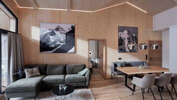Un salon moderne avec un plancher et des murs en bois, un canapé d’angle, une table à manger avec des chaises et de grandes images encadrées accrochées aux murs.