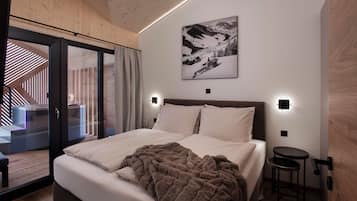 Un dormitorio moderno con una cama grande, vistas a una pista de esquí y un techo de madera.