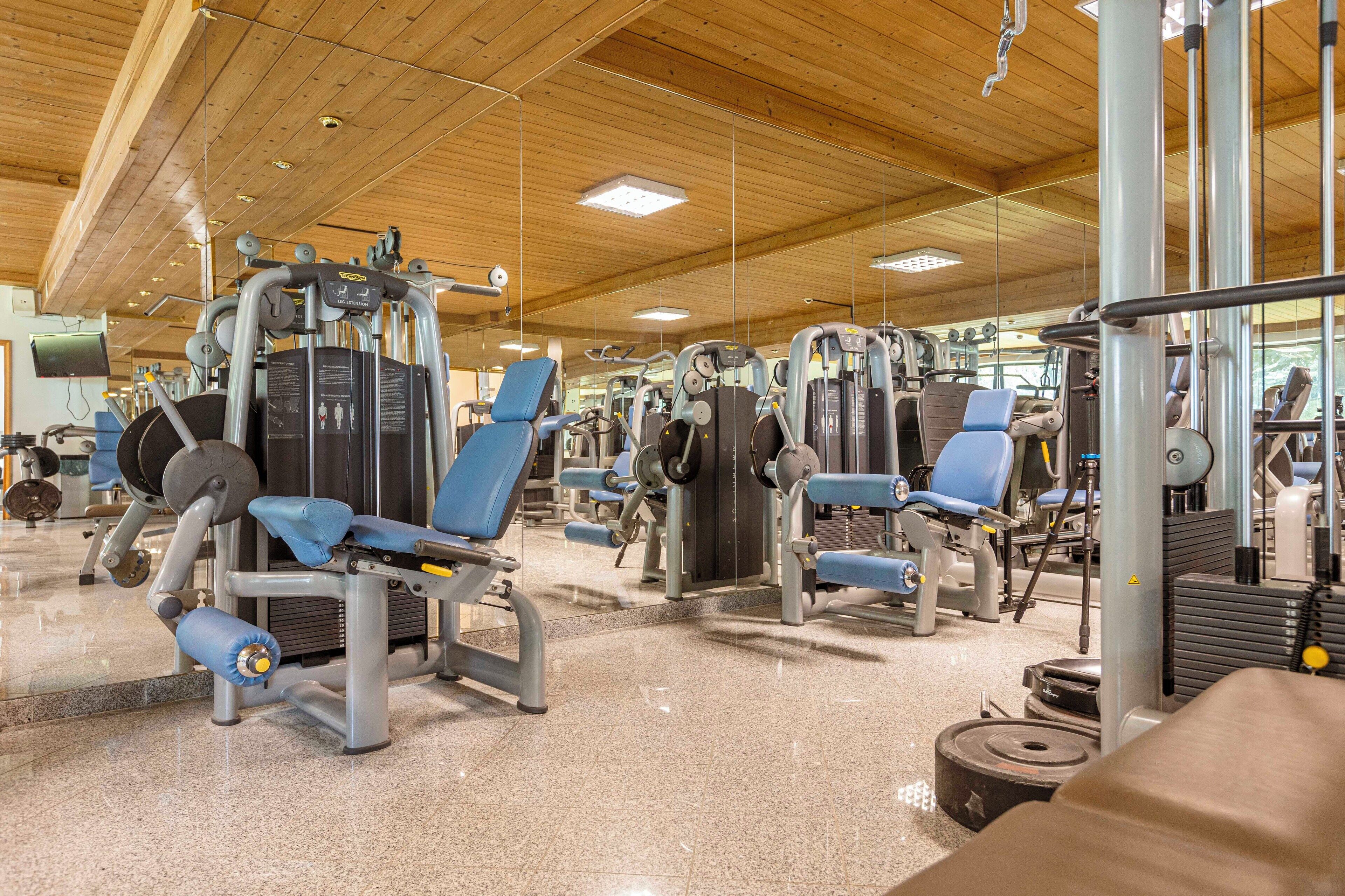 Et fitnessrum med forskellige træningsmaskiner, træloft og en slebet gulv.
