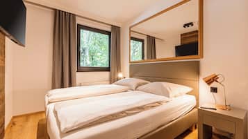 Une chambre à coucher avec un lit, une table de chevet, un miroir et une fenêtre avec des rideaux.