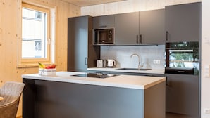A modern kitchen with a central island, stainless steel appliances, and a window providing natural light.