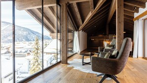 A spacious room with a large window offering a view of snow-covered buildings and mountains. - Bergresort Zugspitze Ehrwald by ALPS RESORTS (Ehrwald)