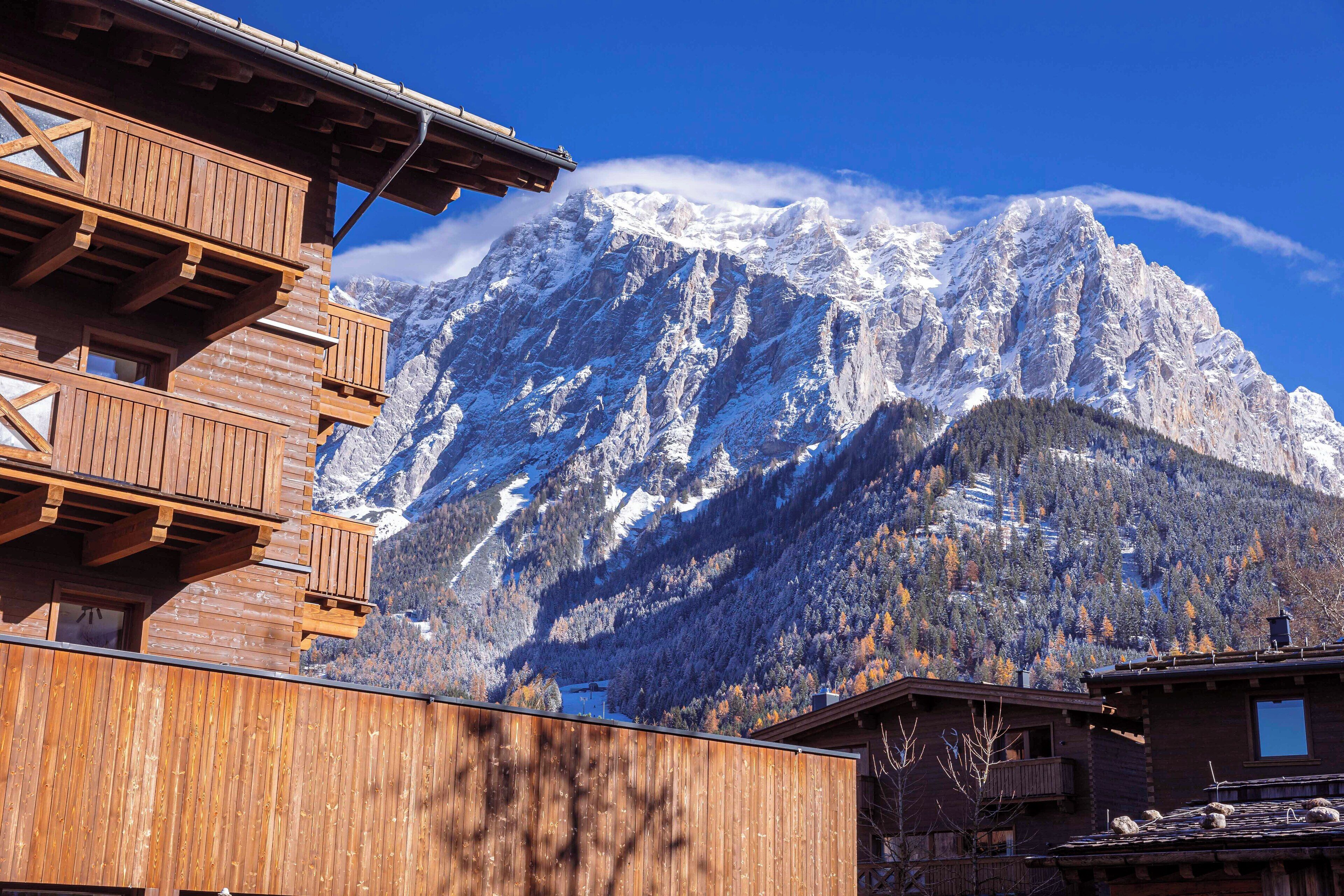 A wooden chalet with a balcony overlooking a snow-capped mountain.