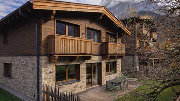 Una casa de madera de dos pisos con paredes de piedra, balcones y una terraza.