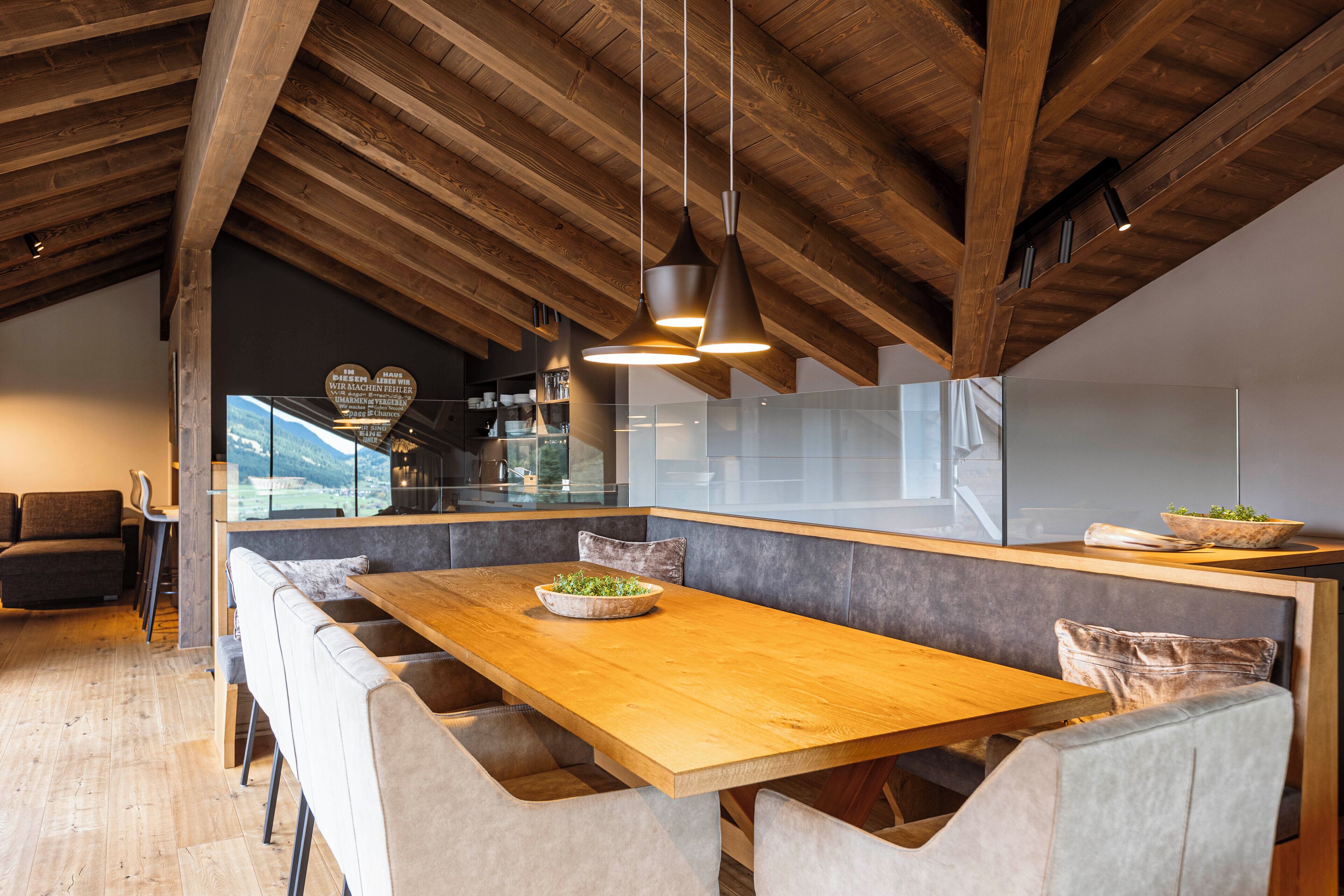 Una cocina moderna con techo de madera, una isla grande con asientos e iluminación colgante.