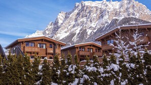 A wooden lodge with balconies, set against a backdrop of snow-covered mountains. - Bergresort Zugspitze Ehrwald by ALPS RESORTS (Ehrwald)