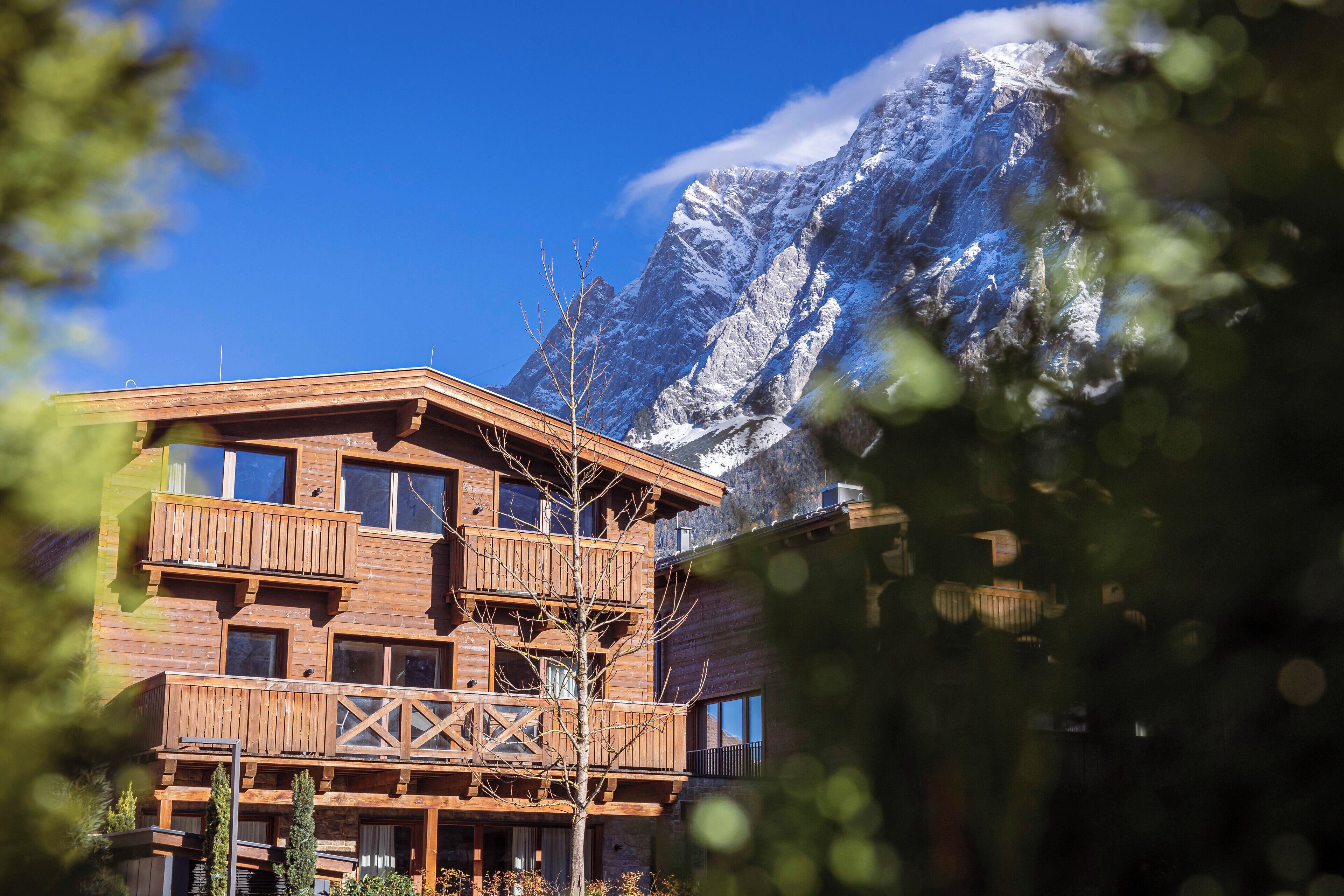 Un chalet en bois doté de plusieurs balcons, situé au pied de montagnes enneigées.