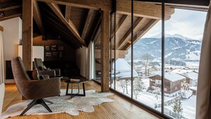 A spacious room with a large window offering a view of a snowy mountain landscape. - Bergresort Zugspitze Ehrwald by ALPS RESORTS (Ehrwald)