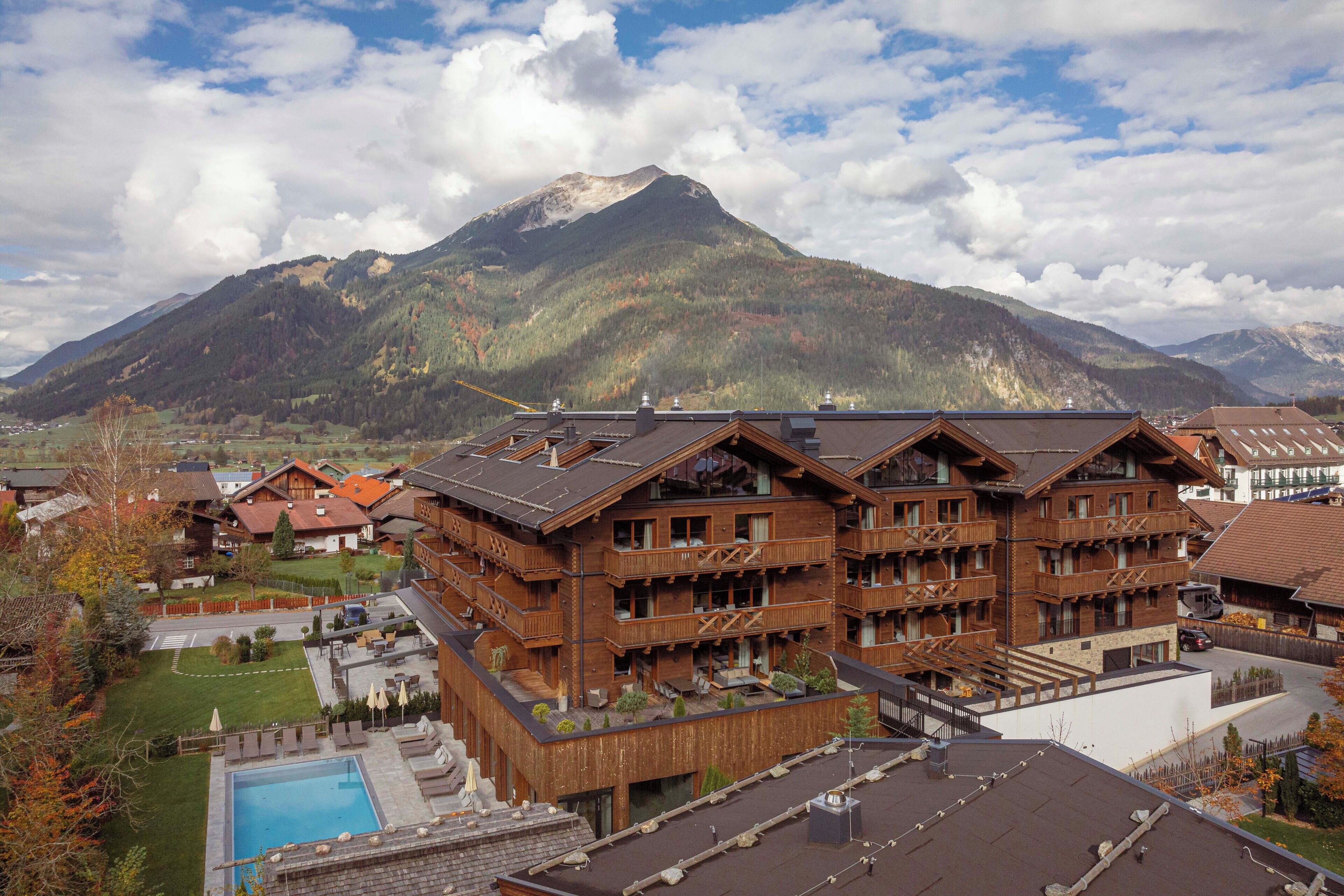A mountain resort with wooden buildings, a swimming pool, and a view of the mountains.