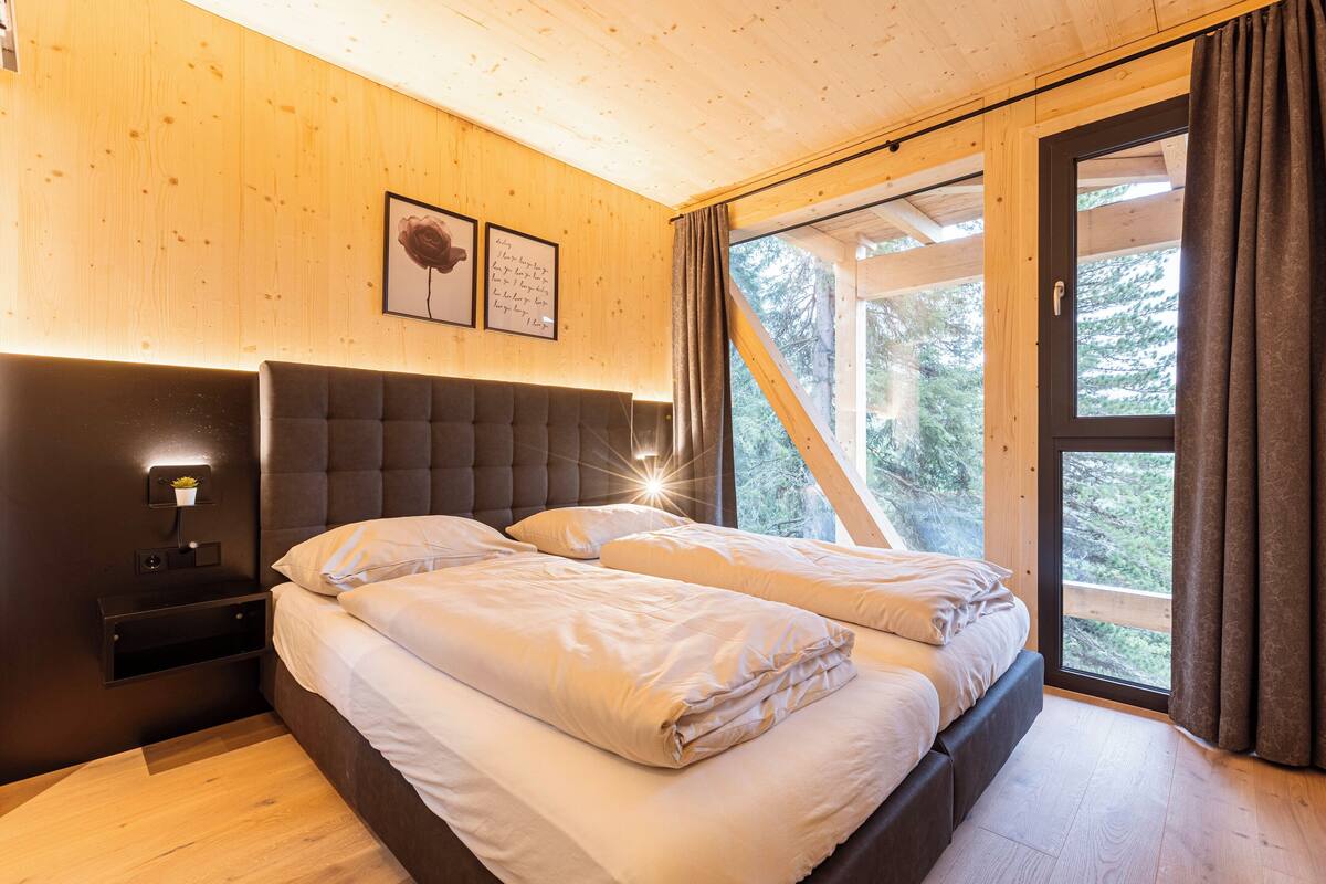A bedroom with a large bed, a nightstand, and a wall-mounted shelf with a plant.