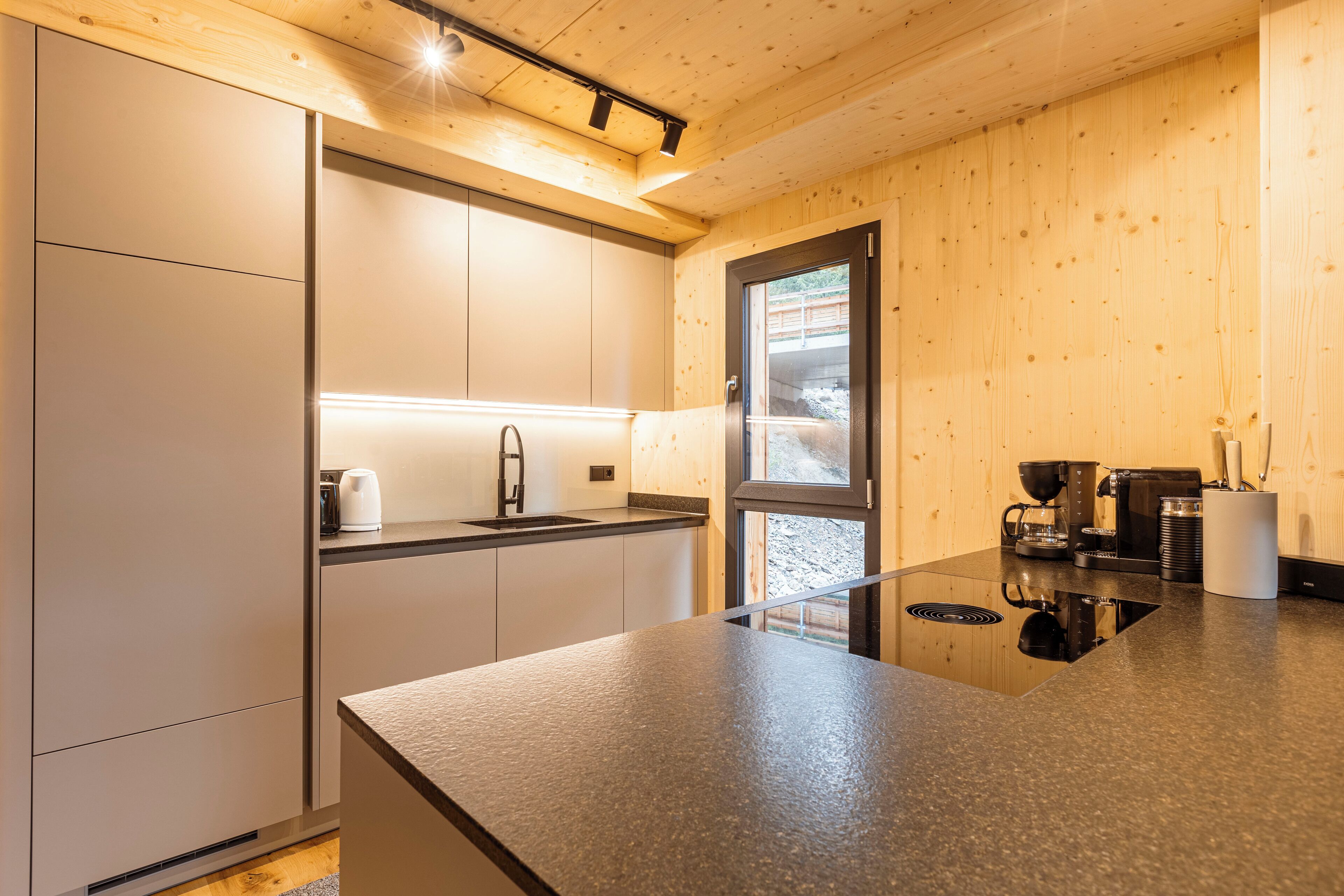 A modern kitchen with a large island, stainless steel appliances, and wooden paneling.