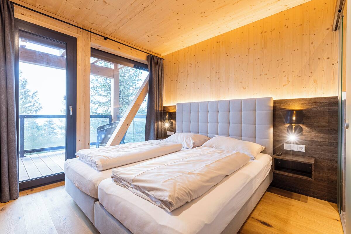 A bedroom with a large bed, a nightstand, and a window with curtains.