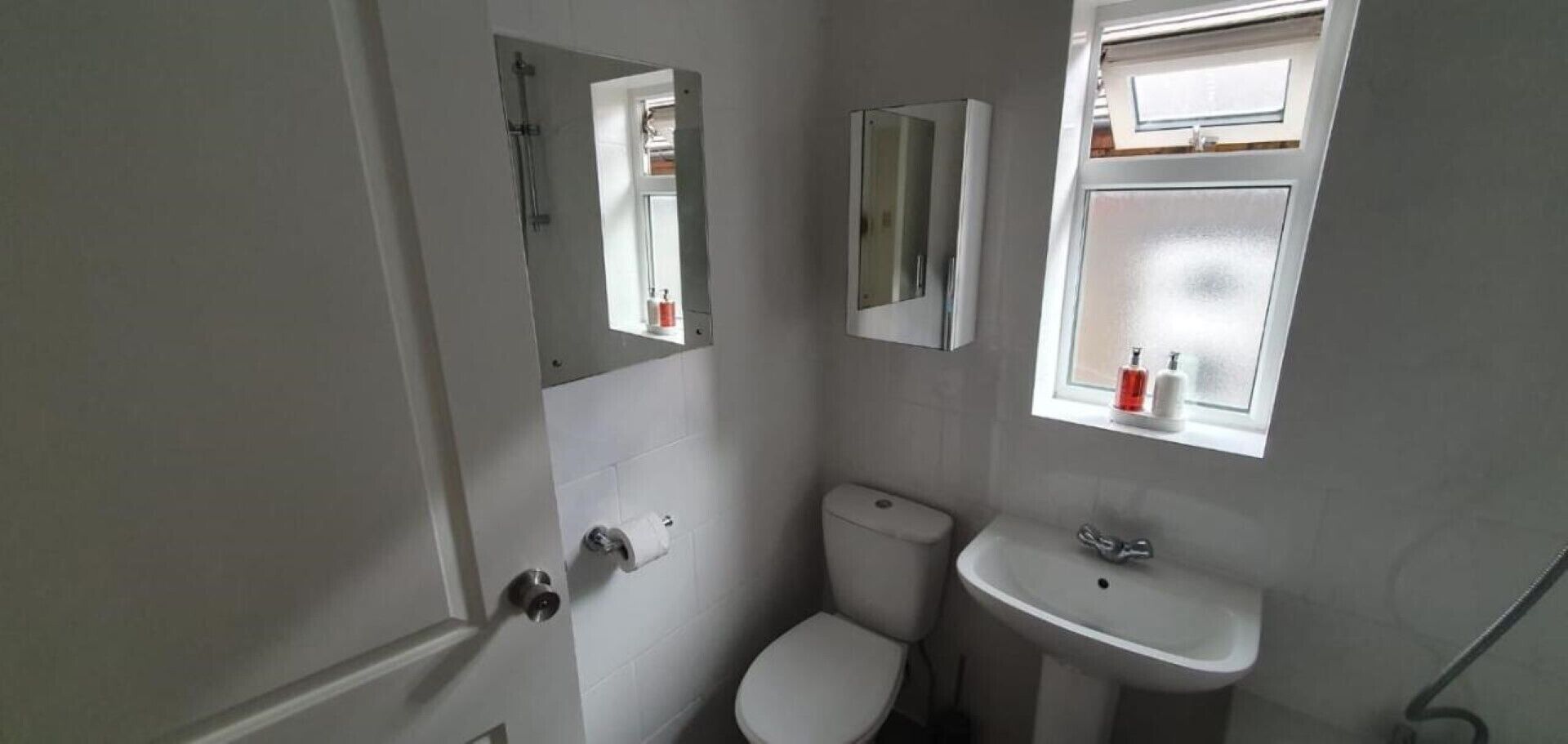 Ein kleines, kompaktes Badezimmer mit Toilette, Waschbecken und einem Spiegel darüber.