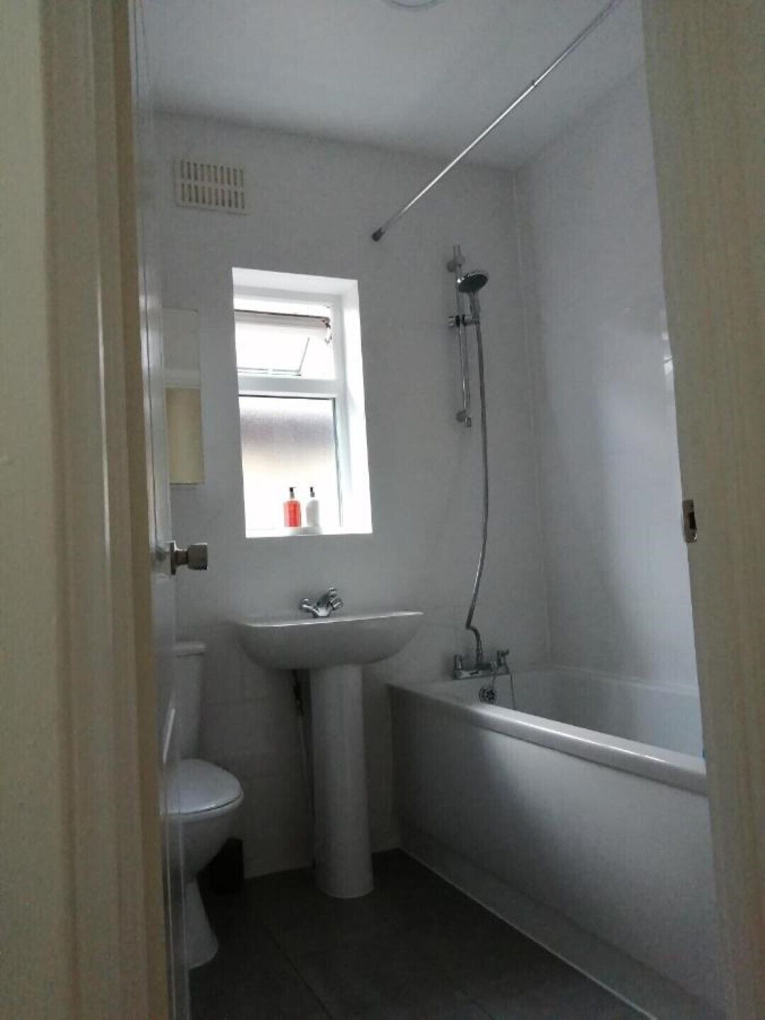 A small, white bathroom with a toilet, sink, and bathtub.