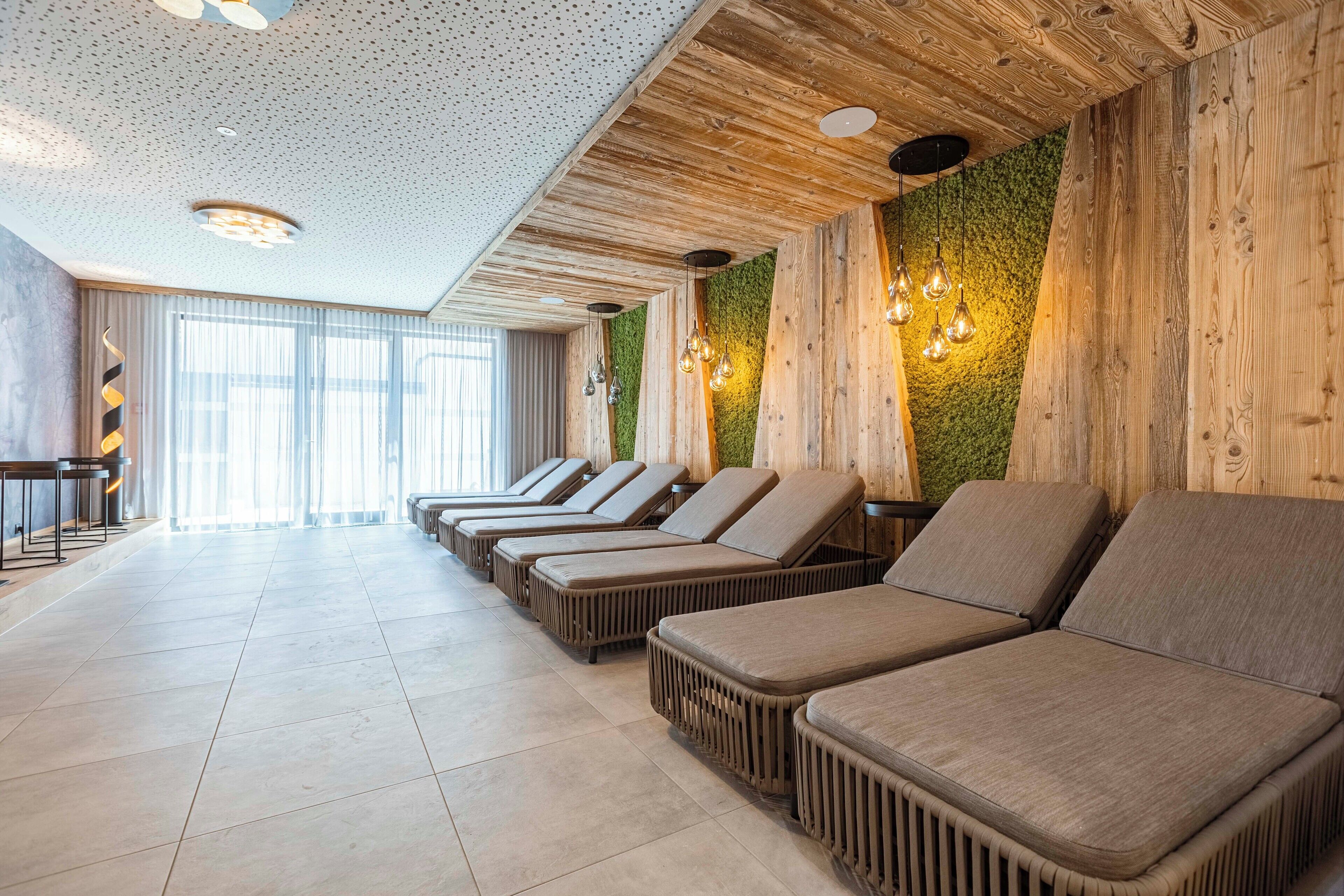 A spa area with lounge chairs, wooden walls, and a green wall accent.