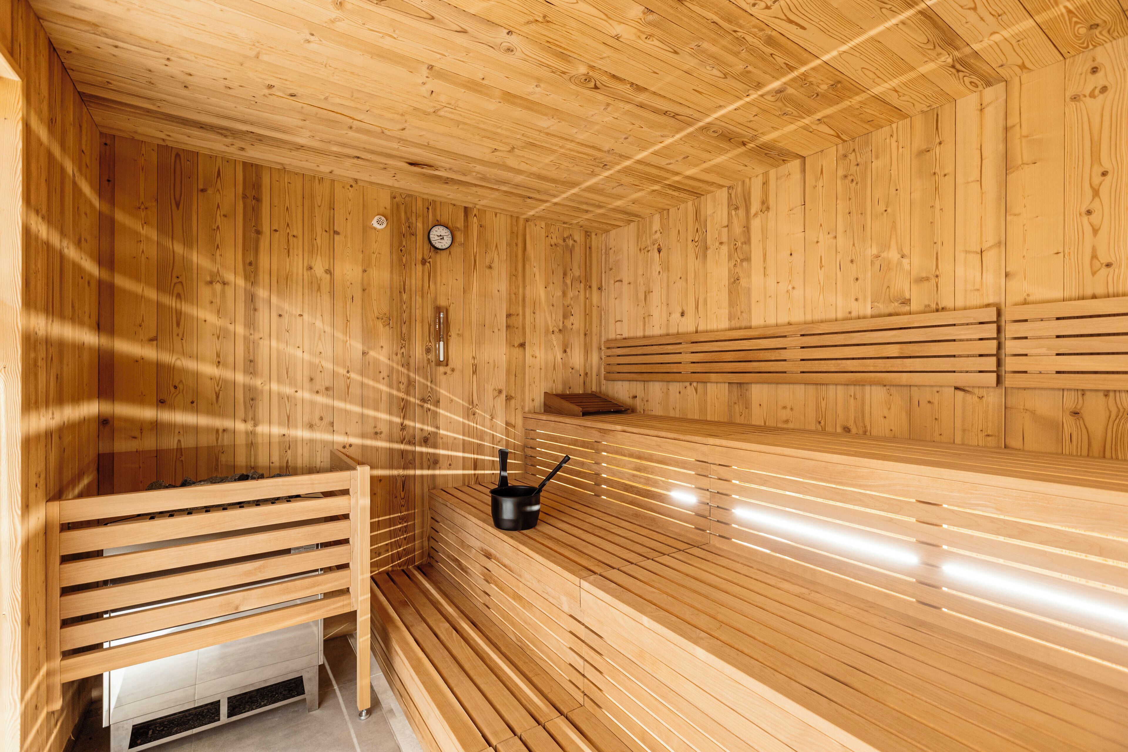 Un sauna avec des bancs en bois et un appareil de chauffage noir.