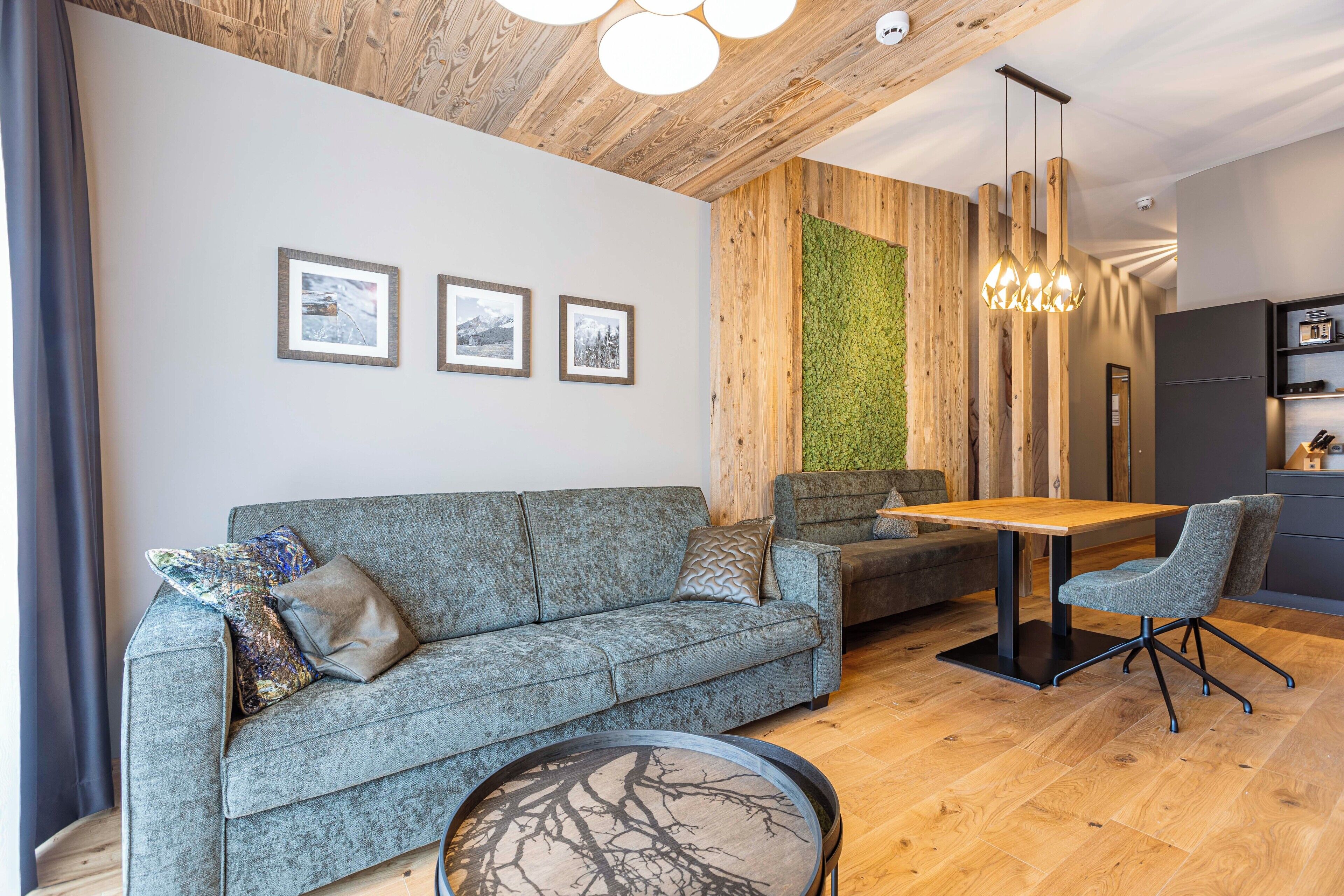 Een moderne woonkamer met een grijze bank, een houten eettafel en een ronde salontafel.
