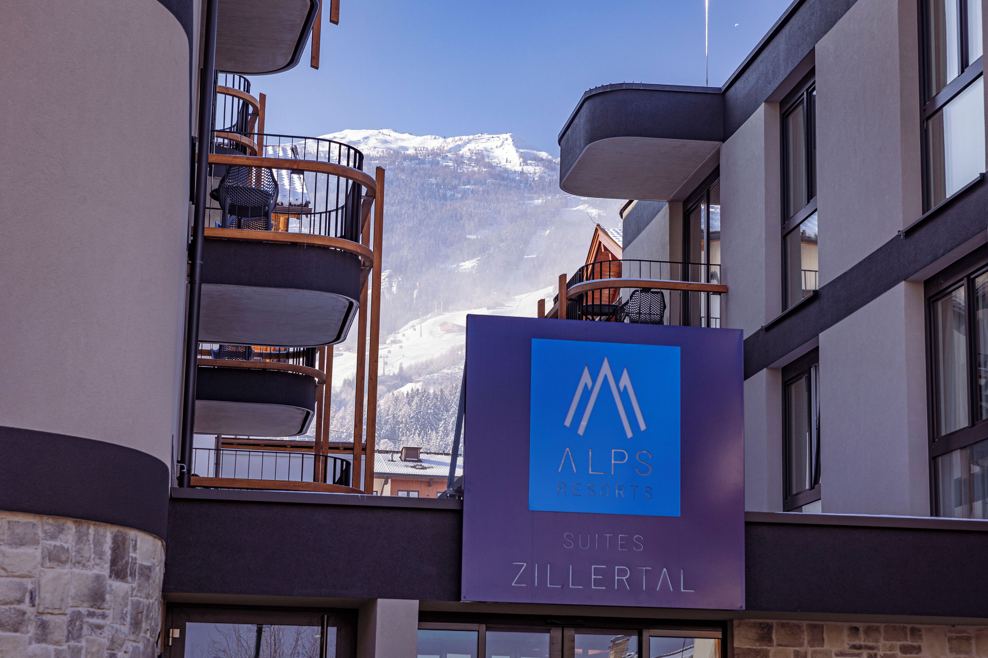 Ein modernes Gebäude mit einem Schild für "ALPS RESORTS SUITES ZILLERTAL".