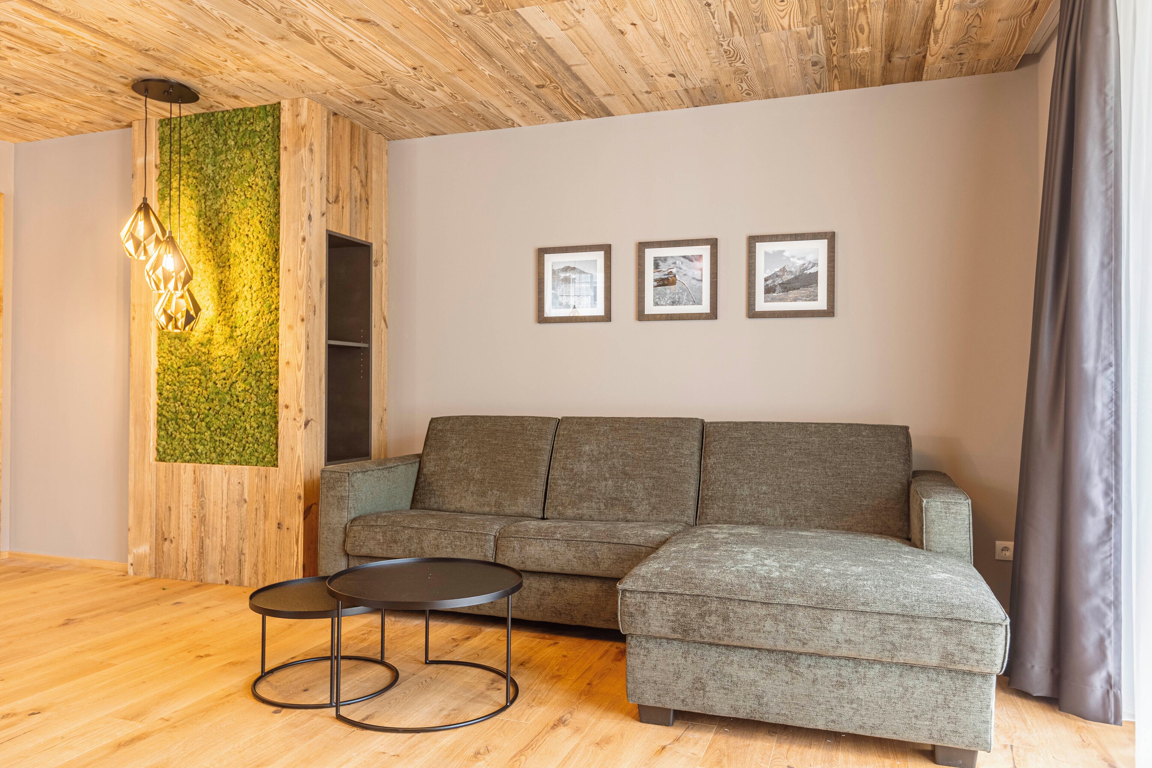 A modern living room with a grey sectional sofa, a round coffee table, and a wooden ceiling.