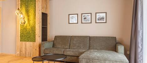A modern living room with a grey sectional sofa, a round coffee table, and a wooden ceiling.