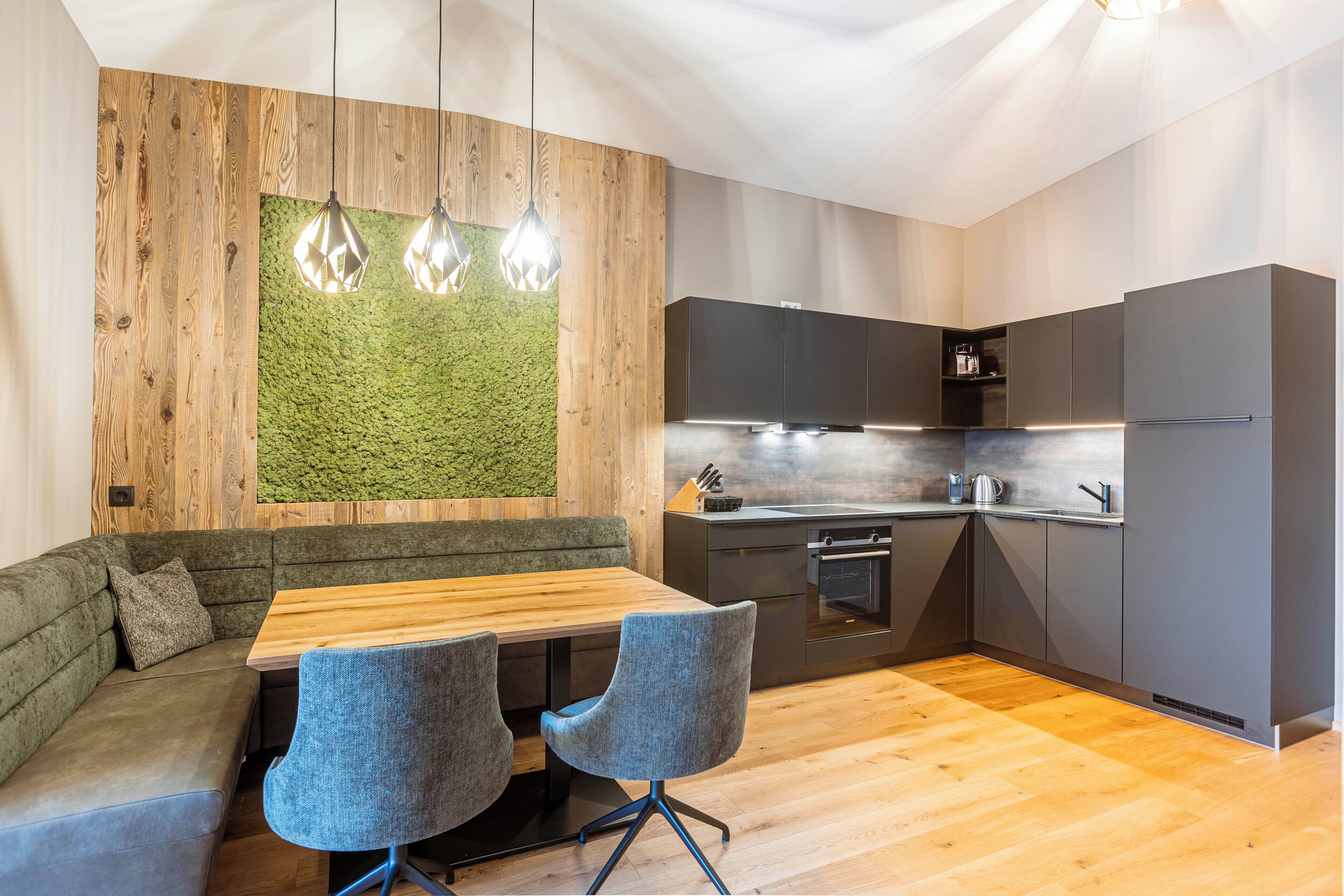 Eine moderne Küche mit einer Holzwand, einer Wand mit grünem Moos und einem Holzespeisetisch mit zwei Stühlen.