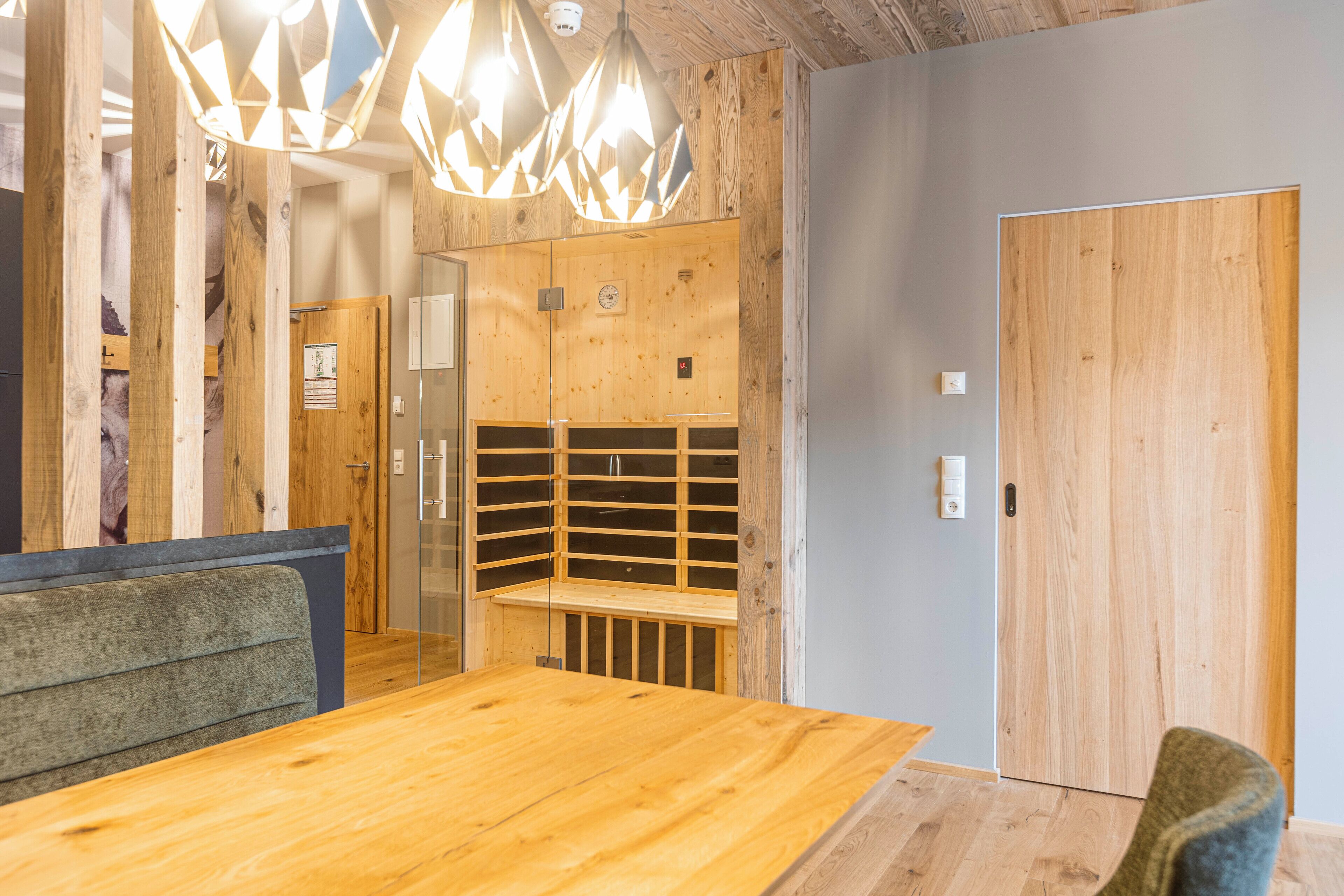 A wooden interior with a dining table, benches, and a wooden door.