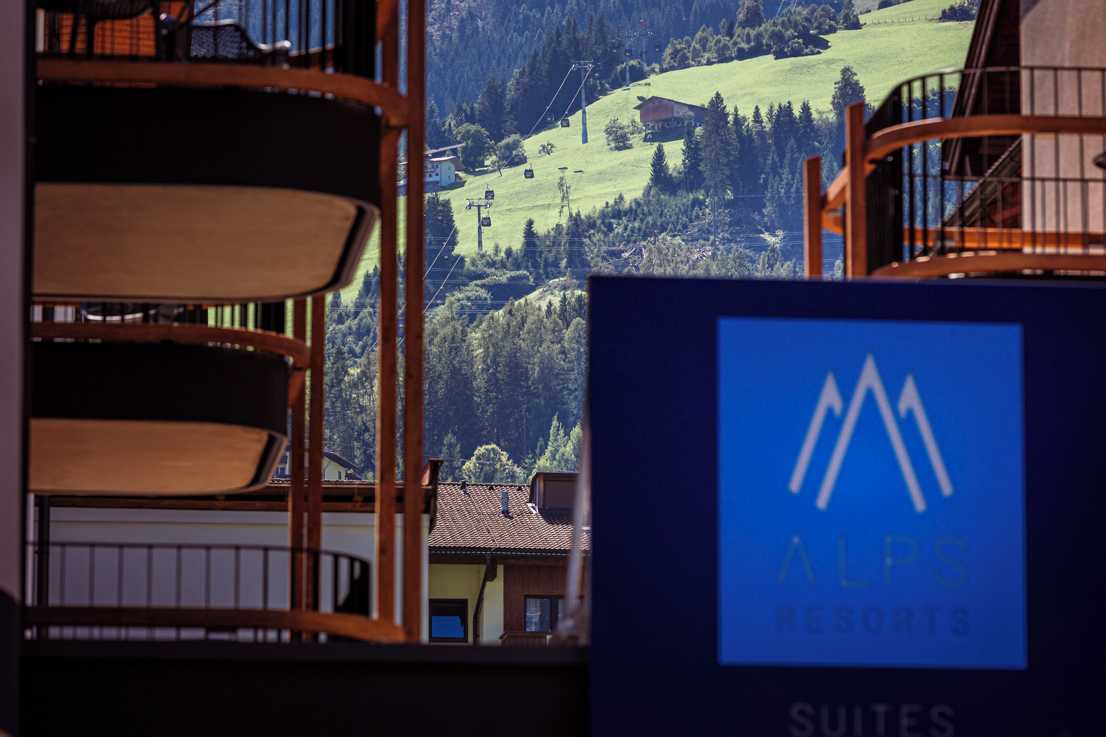 A view of a mountain resort with a sign for ALPS RESORTS Suites.