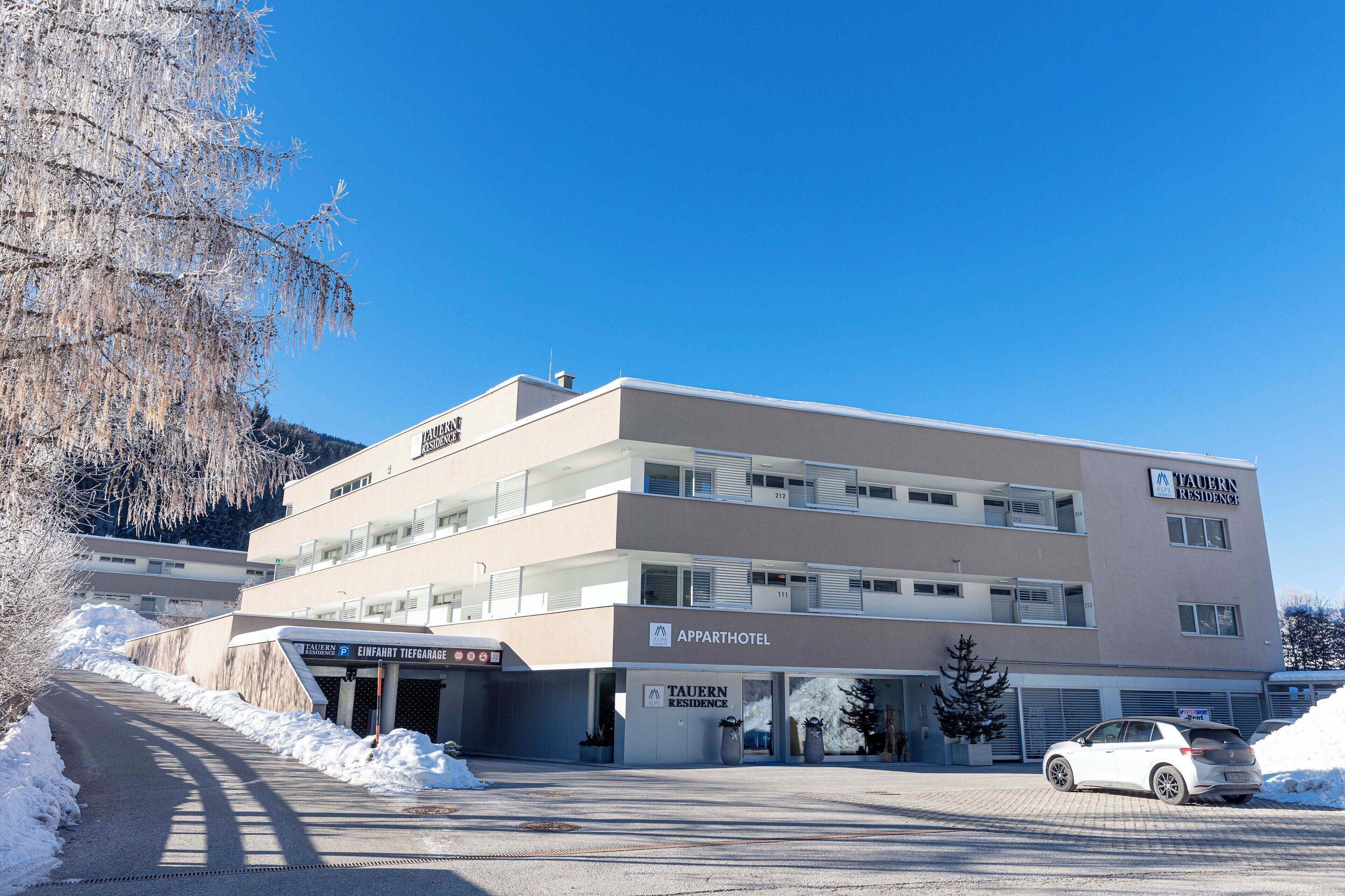 A modern multi-story building with a sign for 'Apparthotel' and 'Taurn Residence'.