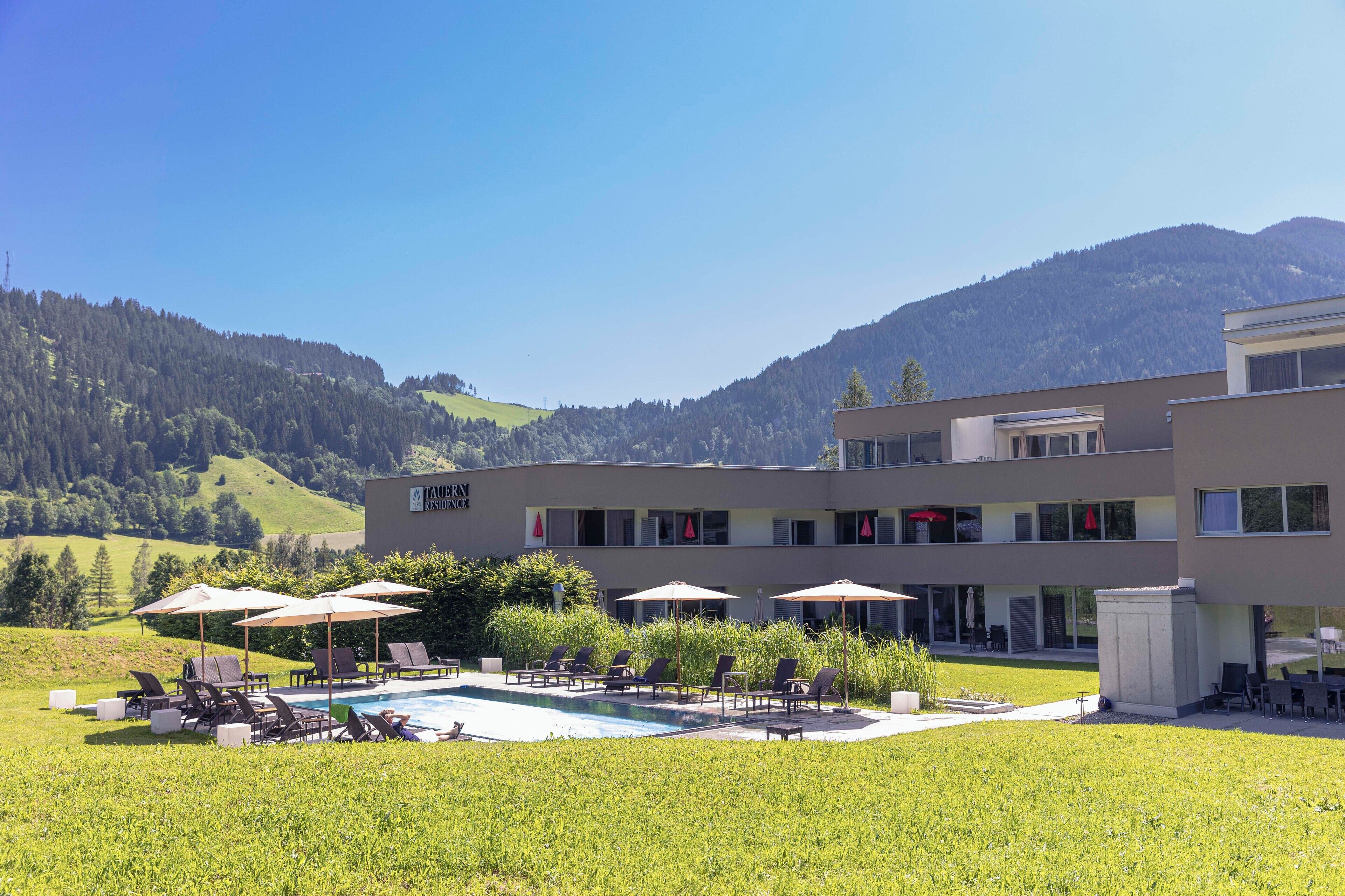 Un hôtel moderne doté d’une piscine, d’un espace extérieur aménagé et offrant une vue sur les montagnes.
