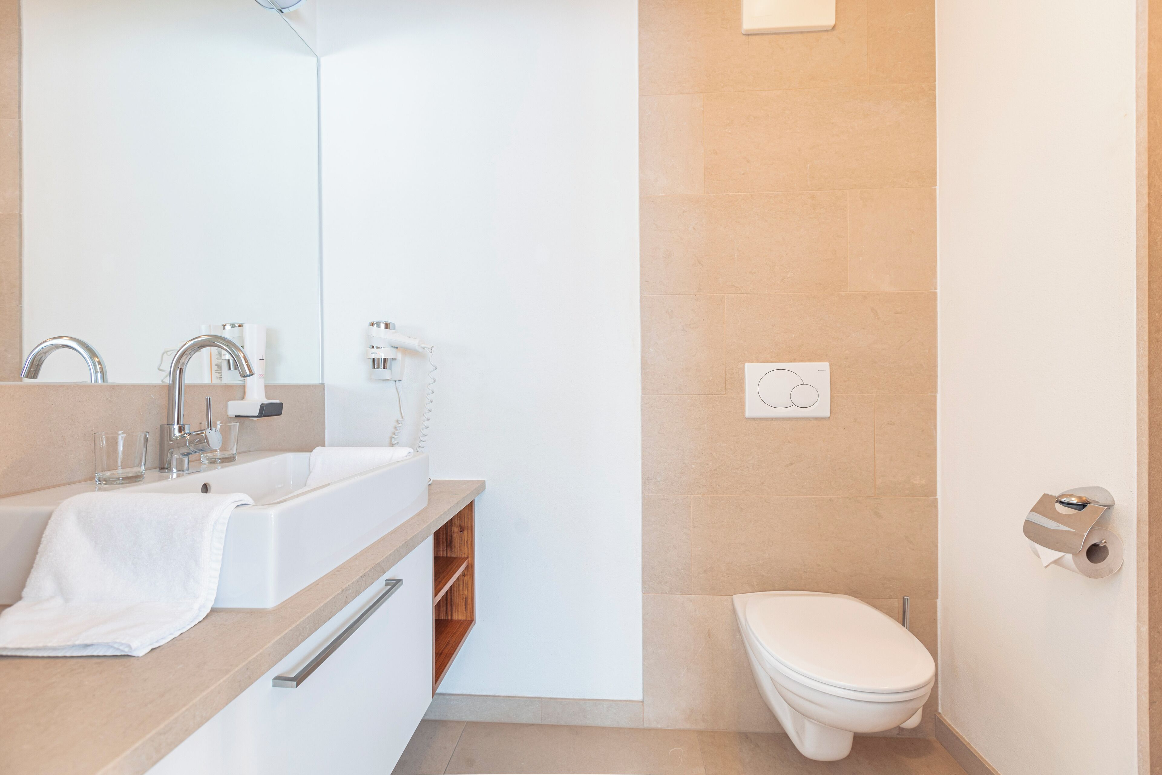 A modern bathroom with a sink, mirror, and toilet.