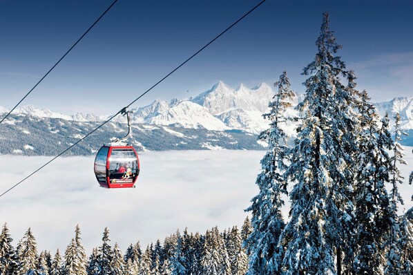 A cable car in a snowy mountainous area with snow-covered trees and peaks in the background. - Tauernresidence Radstadt by ALPS RESORTS (Radstadt)