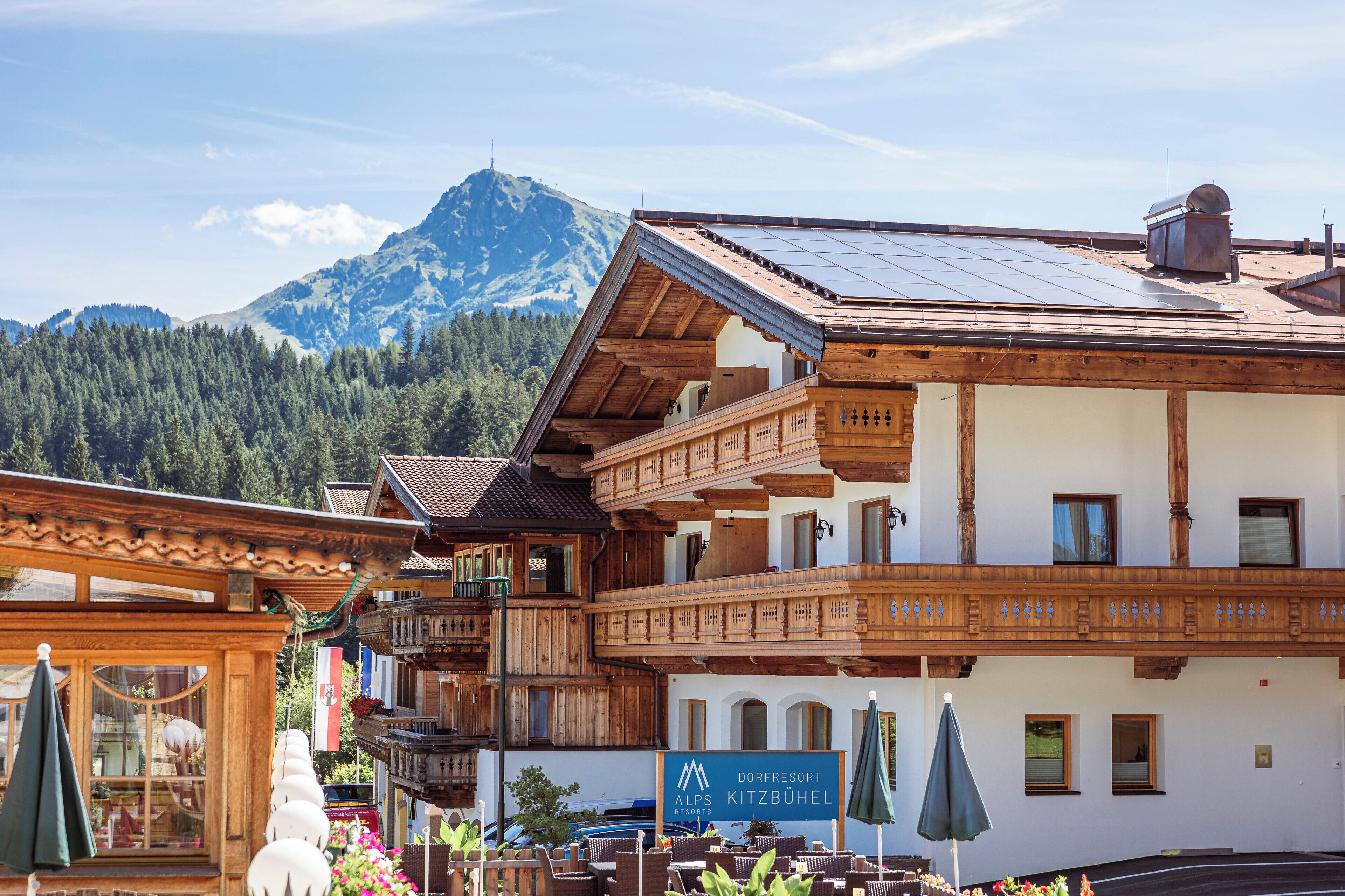 A traditional wooden building with a sign for 'Dorfresort Alpenpitz Kitzbühel'.