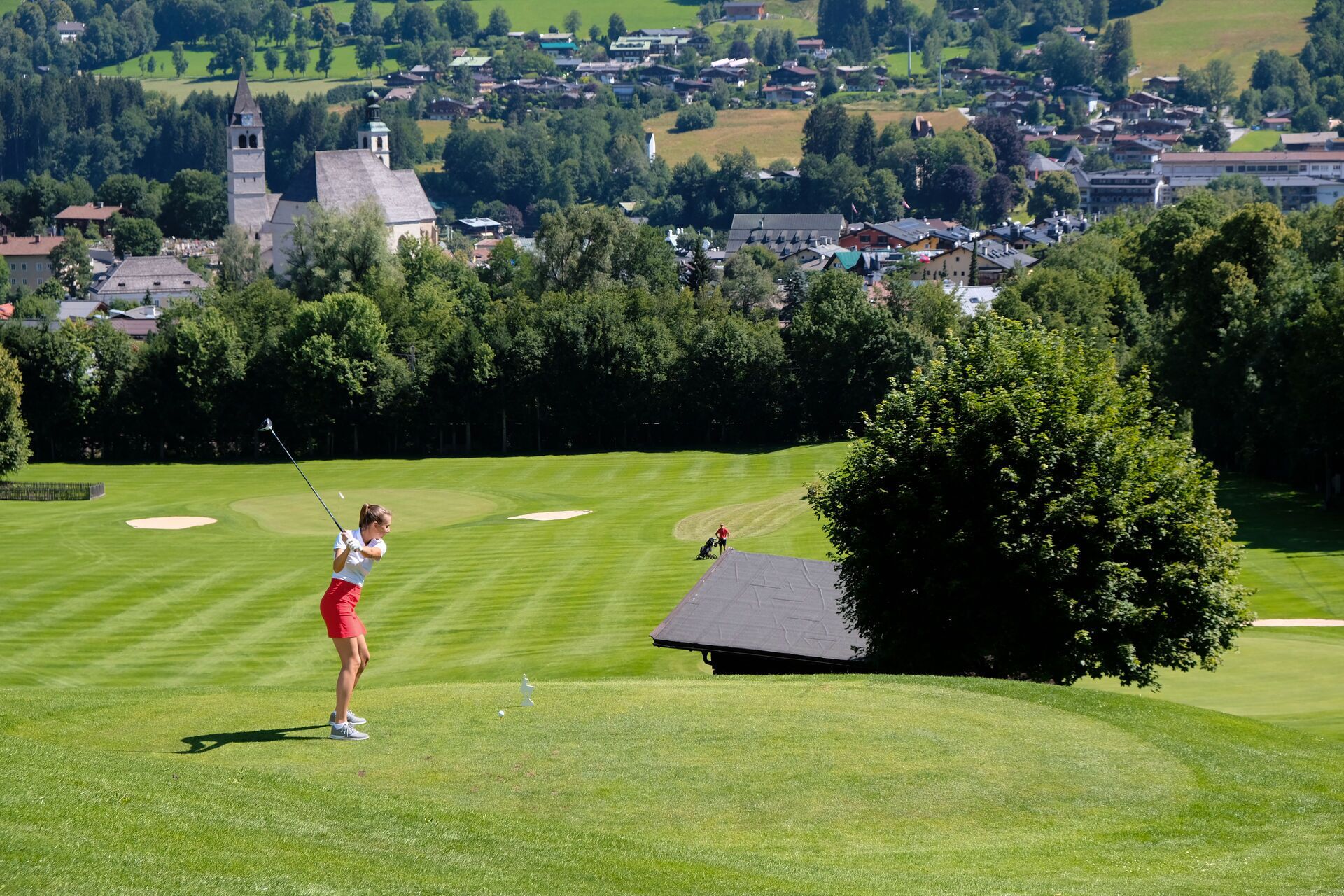 Un campo de golf con vistas a un pueblo y una iglesia al fondo.