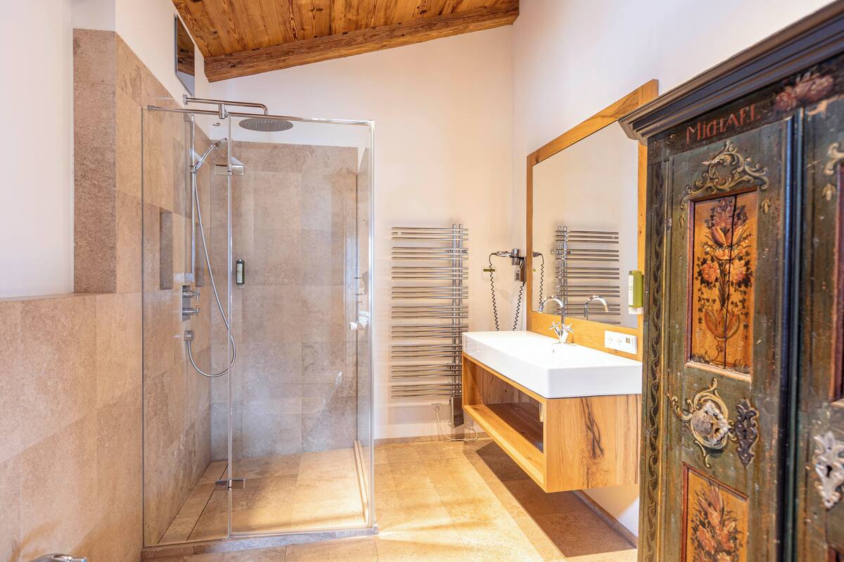 A modern bathroom with a glass-enclosed shower, a wooden vanity, and a large mirror.