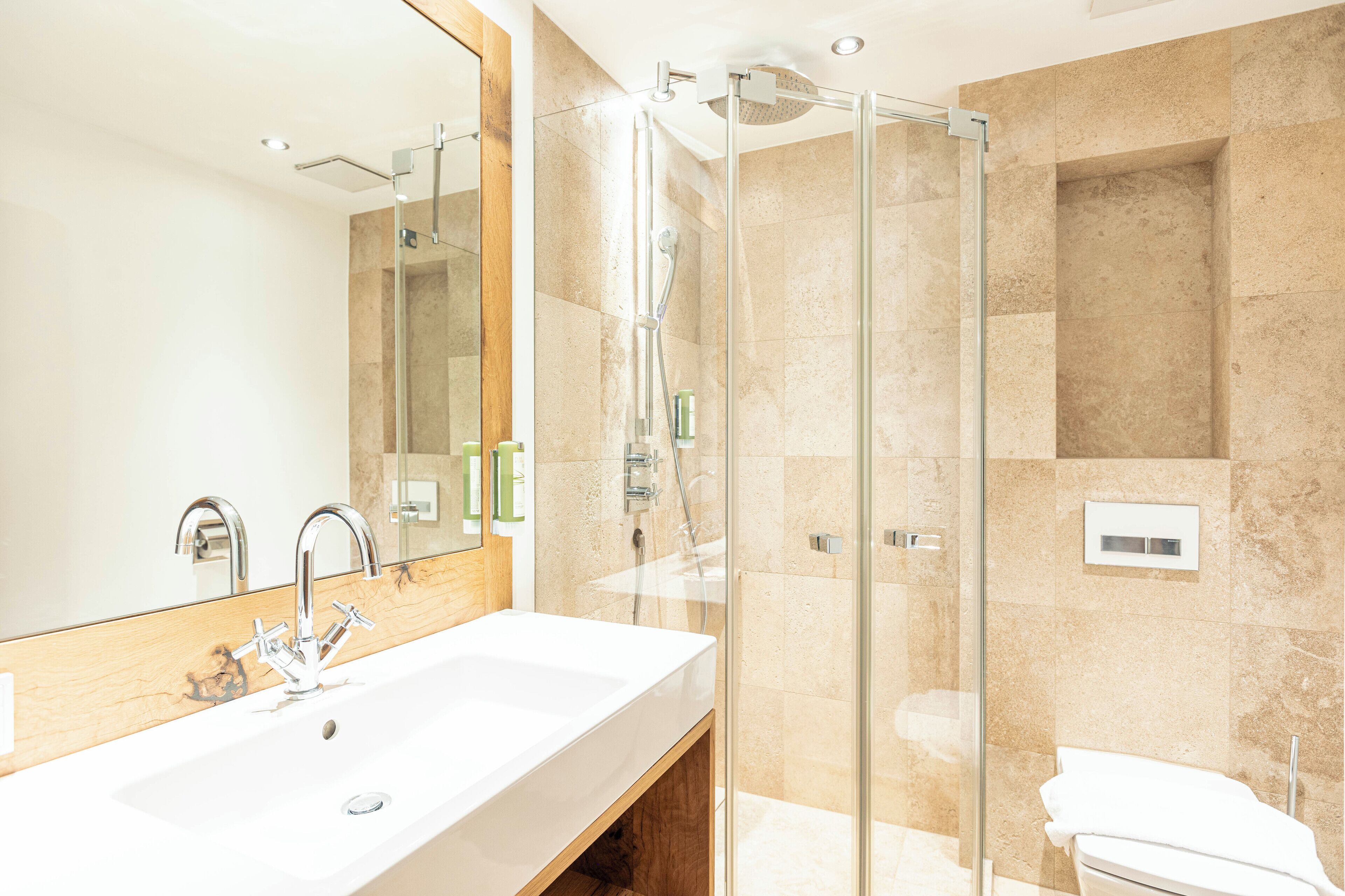 A modern bathroom with a large sink, a glass shower enclosure, and a toilet.